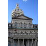 Baltimore: City Hall Baltimore City Hall, situated on a city block bound by Lexington Street, Gilford Avenue, Fayette Street and War Memorial Plaza, was constructed between 1867-1875 and officially dedicated on October 25, 1875. It is the official seat of government of the City of Baltimore, housing the offices of the Mayor, City Council, and City Comptroller. In 1830 the city of Baltimore purchased the Peale Building to serve as its City Hall, but outgrew it within two decades. In 1860, taxpayers approved the new City Hall, but construction was stalled by the Civil War. The six-story structure was designed by the 22-year old architect, George A. Frederick, in the Second Empire style, a Baroque revival, with prominent Mansard roofs with richly-framed dormers, and two floors of a repeating Serlian window motif over an urbanely rusticated basement. At a cost of $2.27 million, Baltimore city Hall is built largely of brick with the exterior walls faced with white marble, which alone, quarried in Baltimore, cost $957,000. The segmented dome capping the building is the work of Baltimore engineer Wendel Bollman, known for his iron railroad bridges. By the end of World War II, City Hall began showing signs of age. In 1974 the city voted to renovate the old city hall rather than build a new one. Architectural Heritage Inc., in association with Meyers, D'Aleo and Patton Inc., were retained to begin the design. The ceremonial chambers were restored and the office space was doubled. In the process the dome was disassembled and put back together. Two years and $10.5 dollars later the building was reopened.