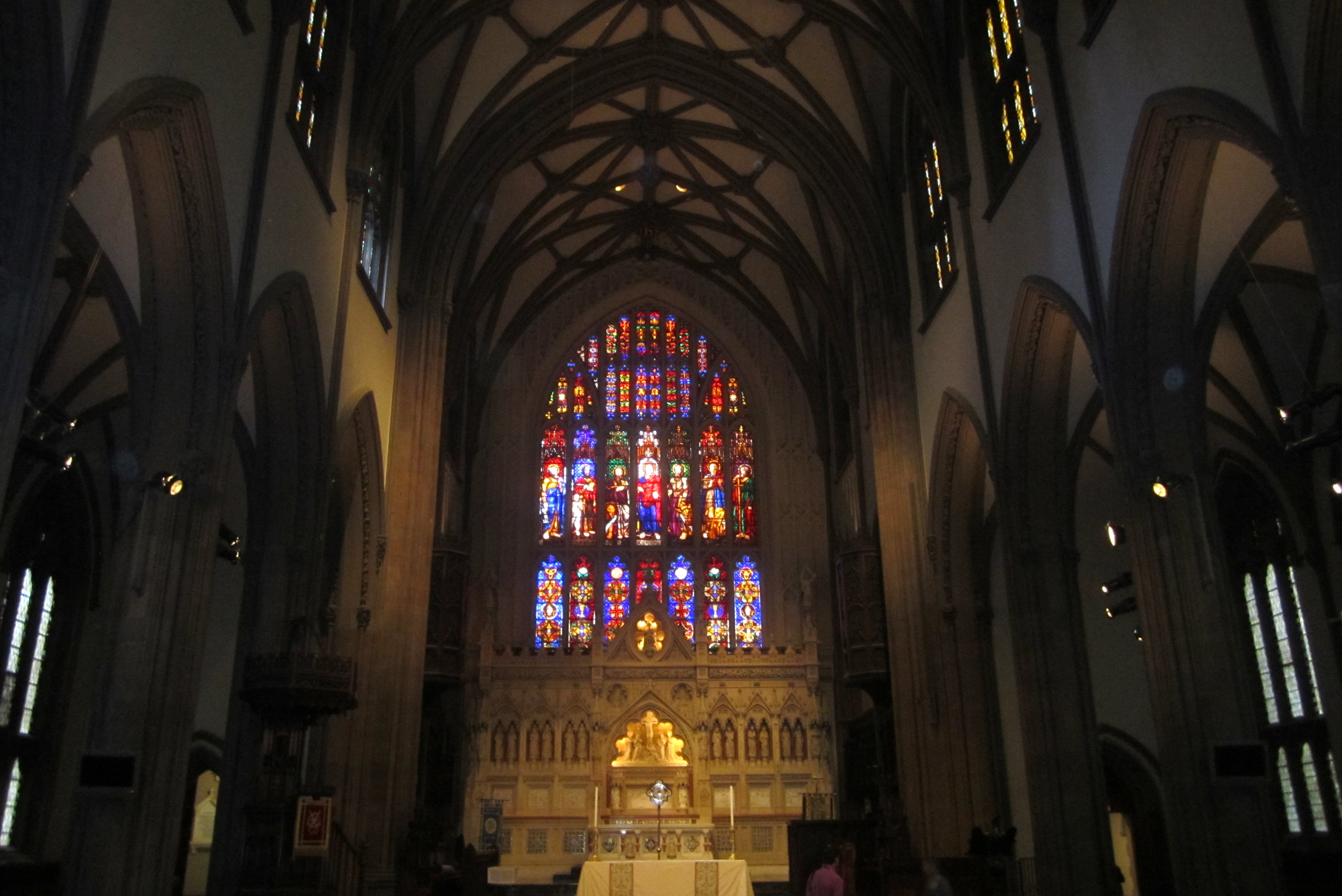 NYC - FiDi: Trinity Church Trinity Church, prominently located at the terminus of Wall Street at 79 Broadway, is the oldest Episcopal church in New York City, having been consecrated on Ascension Day May 1, 1846. Designed by architect Richard Upjohn, Trinity is considered a classic example of Gothic Revival architecture. At the time of its completion, the 281-foot spire was the highest point in New York until being surpassed in 1890 by the New York World Building. The Trinity Church parish received its initial charter from King William III of England in 1697. The first Trinity Church building, a modest rectangular structure with a gambrel roof and small porch was constructed in 1698. The building was destroyed in the Great New York City Fire of 1776, in the early days of the military occupation by the British during the American Revolutionary War. Construction on the second building began in 1788, which was consecrated in 1790 and then torn down after being weakened by severe snows during the winter of 1838–39. By the early 1840's, the church's expanding parish had split. The newly formed parish would build Grace Church, to the north on Broadway at 10th street, while the original parish would re-build the Trinity that stands today. Upjohn designed the new Church in Neo-Gothic fashion, complete with sandstone and stained-glass windows--two features unheard of at the time. Adorned with Gothic spires and pointed arches, and sporting a very linear upward-appearing exterior, the design reflected "High Church" fashion, at odds with contemporary Protestant "Low Church" thought. As a compromise, the side walls were kept simple, without the flying buttresses predominant in most Gothic structures. In 1876-1877 a reredos and altar was erected in memory of William Backhouse Astor, Sr., to the designs of architect Frederick Clarke Withers. In 1893, three sets of ornate hevy bronze doors, the Astor Memorial doors, conceived by Richard Morris Hunt and sculpted by J. Massey Rhind, Karl Bitter and Charles Henry Niehaus, were added. The adjoining Trinity Churchyard Cemetery, opened in 1697, is one of three separate burial grounds that make up the non-denominational Trinity Church Cemetery (the others being the Churchyard of St. Paul's Chapel and the Trinity Church Cemetery and Mausoleum at the Chapel of Intercession). Among the 1,186 interred here are Alexander Hamilton, William Bradford, Robert Fulton (memorial tribute), Captain James Lawrence, Horatio Gates, and Albert Gallatin. There are also memorials to the unknown martyrs of the Revolution buried on the grounds, 16 officers of the Continental Army and Navy buried in the church cemeteries, and to the thousands of Americans who died in prison ships in New York Harbor. Trinity Church and Graveyard was designated a landmark by the New York Landmarks Preservation Commission in 1966. National Register #76001252 (1982)