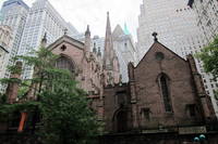 NYC - FiDi: Trinity Church Trinity Church, prominently located at the terminus of Wall Street at 79 Broadway, is the oldest Episcopal church in New York City, having been consecrated on Ascension Day May 1, 1846. Designed by architect Richard Upjohn, Trinity is considered a classic example of Gothic Revival architecture. At the time of its completion, the 281-foot spire was the highest point in New York until being surpassed in 1890 by the New York World Building. The Trinity Church parish received its initial charter from King William III of England in 1697. The first Trinity Church building, a modest rectangular structure with a gambrel roof and small porch was constructed in 1698. The building was destroyed in the Great New York City Fire of 1776, in the early days of the military occupation by the British during the American Revolutionary War. Construction on the second building began in 1788, which was consecrated in 1790 and then torn down after being weakened by severe snows during the winter of 1838–39. By the early 1840's, the church's expanding parish had split. The newly formed parish would build Grace Church, to the north on Broadway at 10th street, while the original parish would re-build the Trinity that stands today. Upjohn designed the new Church in Neo-Gothic fashion, complete with sandstone and stained-glass windows--two features unheard of at the time. Adorned with Gothic spires and pointed arches, and sporting a very linear upward-appearing exterior, the design reflected "High Church" fashion, at odds with contemporary Protestant "Low Church" thought. As a compromise, the side walls were kept simple, without the flying buttresses predominant in most Gothic structures. In 1876-1877 a reredos and altar was erected in memory of William Backhouse Astor, Sr., to the designs of architect Frederick Clarke Withers. In 1893, three sets of ornate hevy bronze doors, the Astor Memorial doors, conceived by Richard Morris Hunt and sculpted by J. Massey Rhind, Karl Bitter and Charles Henry Niehaus, were added. The adjoining Trinity Churchyard Cemetery, opened in 1697, is one of three separate burial grounds that make up the non-denominational Trinity Church Cemetery (the others being the Churchyard of St. Paul's Chapel and the Trinity Church Cemetery and Mausoleum at the Chapel of Intercession). Among the 1,186 interred here are Alexander Hamilton, William Bradford, Robert Fulton (memorial tribute), Captain James Lawrence, Horatio Gates, and Albert Gallatin. There are also memorials to the unknown martyrs of the Revolution buried on the grounds, 16 officers of the Continental Army and Navy buried in the church cemeteries, and to the thousands of Americans who died in prison ships in New York Harbor. Trinity Church and Graveyard was designated a landmark by the New York Landmarks Preservation Commission in 1966. National Register #76001252 (1982)