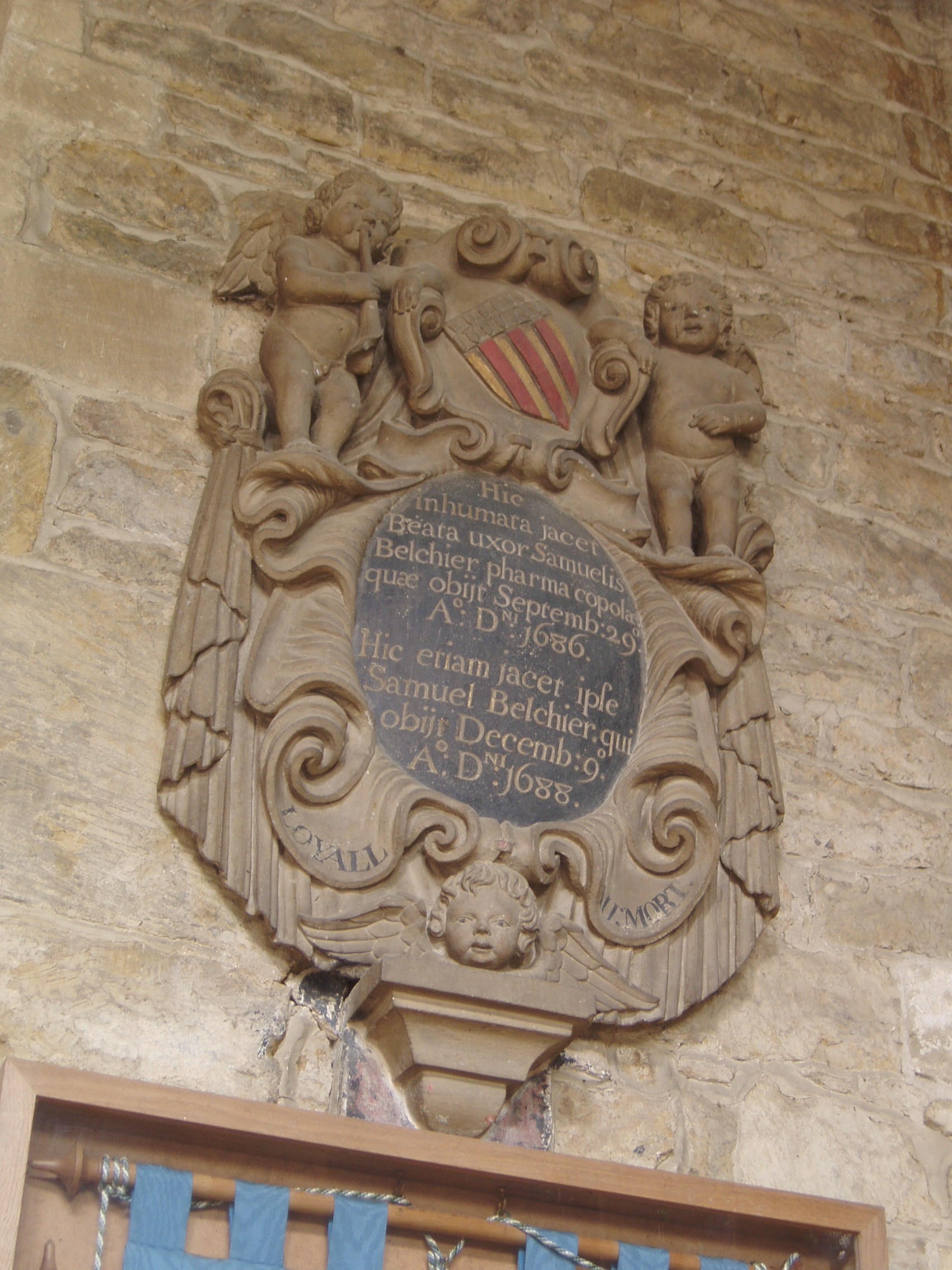 Belchier Monument SS Peter & Paul at Deddington displays the warm toffee-colouring of north Oxfordshire's ironstone to good effect. The tower with it's gilt-weathervaned pinnacles is the main landmark of this small town. The main body of this very grand church dates mostly from the 13th and 14th centuries, but the tower and west end of the aisles were built after the original steeple collapsed in 1634. Rebuilding was interrupted by the Civil War and not completed untuil 1683-5. This 17th century work blends well with the medieval church, only in some of the carved details of doors and windows is the later date apparent. Statues of the church's patron saints were re-used on the west side (only their lower halfs are medieval). The spacious interior contains two medieval monuments and a curious north porch with a shallow gothic dome (part of the 17th century reconstruction). The most significant artworks are in stained glass; there are two windows by C.E.Kempe, but far more impressive are the superb Arts & Crafts period windows in the north aisle by Archibald J. Davies of the Bromsgrove Guild, some of the very finest glass of it's date. For more see below:- www.deddington.org.uk/history/churchesandchapels/jonesmem...