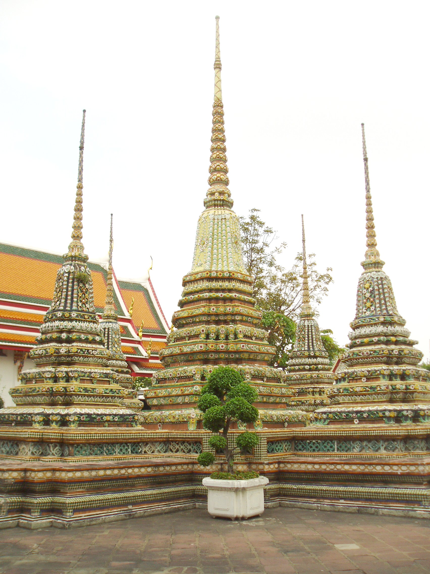 Miniature Stupas, Wat Pho, Bangkok Wat Pho is the largest and oldest temple complex in Bangkok, and along with the temmple of the royal palace the most visited. The sprawling complex covers a huge area and it is quite easy to lose oneself within it's series of courtyards, gateways and stunning temple buildings. The present complex largely dates back to 1788, having been founded in response to the sacking of the former capital Ayutthaya by the Burmese in 1767 where a similar complex was destroyed. It is known as a place of learning and has a renowned school of Thai massage within the site. The temple complex is entered through one of many gateways guarded by huge Chinese statues, believed to have been imported as ballast on ships trading with China..The outer gates have fierce warrior figures, whilst the inner courtyards have the bizarre 'farang' ('foreigner') figures with their peculiar 'top hats', believed to represent the first European visitors to the east. Many of the inner courtyards are surrounded by a cloister containing over 400 sculptures of the seated Buddha, whilst the main Bot, the spiritual nucleus of the temple, is beautifully decorated within with frescoes of rich landscapes in red and gold. The biggest and most spectacular attraction of the temple however is the Hall of the Reclining Buddha, housing an enormous gilded recumbent figure of the Buddha over 160ft long, filling the entire centre of the chamber. en.wikipedia.org/wiki/Wat_Pho