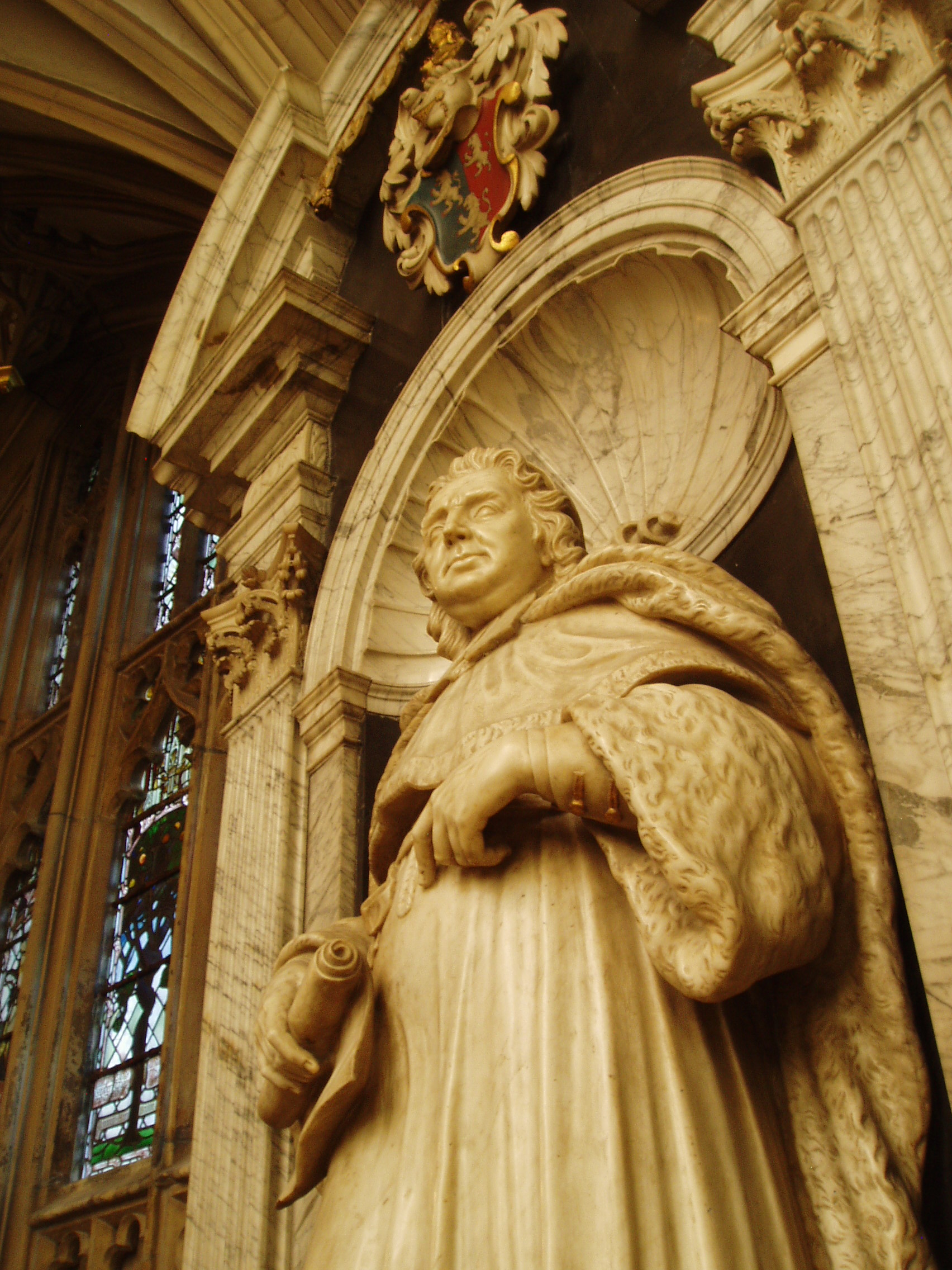 Judge John Powell Monument to Judge John Powell carved in 1713 by Thomas Green of Camberwell, and situated on the north side of the Lady Chapel at Gloucester Cathedral. Impressive though the monument may be, it's installation was without sensitivity to the surrounding architecture and must have involved considerable cutting away of the late gothic stonework. Gloucester Cathedral is one of England's finest churches, a masterpiece of medieval architecture consisting of a uniquely beautiful fusion of Norman Romanesque and Perpendicular Gothic from the mid 14th century onwards. Until the Reformation this was merely Gloucester's Abbey of St Peter, under Henry VIII it became one of six former monastic churches to be promoted to cathedral status, thus saving the great church from the ravages of the Dissolution. The most obviously Norman part is the nave, immediately apparent on entering the building with it's round arches and thick columns (the exterior is the result of Gothic remodelling). Much of the remainder of the building is substantially the Norman structure also, but almost entirely modified in the later Middle Ages inside and out, the result of the great revenue brought to the abbey by pilgrims to the tomb of the murdered King Edward II in the choir. It was this transformation of the Norman church that is credited with launching the late gothic Perpendicular style in England. The gothic choir is a unique and spectacular work, the walls so heavily panelled as to suggest a huge stone cage (disguising the Norman arches behind) crowned by a glorious net-like vault adorned with numerous bosses (those over the Altar with superb figures of Christ and angels) whilst the east wall is entirely glazing in delicate stone tracery, and still preserving most of it's original 14th century stained glass. The soaring central tower, also richly panelled with delicate pinnacles, is another testament to the abbey's increasing wealth at this time. The latest medieval additions to the church are equally glorious, the Lady Chapel is entered through the enormous east window and is itself a largely glazed structure, though the original glass has been reduced to a few fragments in the east window, the remainder now contains beautiful Arts & Crafts stained glass by Christopher and Veronica Whall. The early 16th century cloisters to the north of the nave are some of the most beautiful anywhere, being completely covered by exquisite fan vaulting, with a seperate lavatorium (washing room) attached to the north walk as a miniature version of the main passages. There is much more of interest, from 14th century choir stalls with misericords to the comprehensive collection of tombs and monuments of various dates, including the elaborate tomb of Edward II and that of Robert Duke of Normandy, eldest son of William the Conqueror. The stained glass also represents all ages, from the 14th century to the striking contemporary windows by Tom Denny. Further areas of the cathedral can be accessed at certain times, such as the Norman crypt under the choir and the triforium gallery above. My visit coincided with the major 'Crucible' exhibition of contemporary sculpture (September-October 2010), examples of which I will upload in due course.