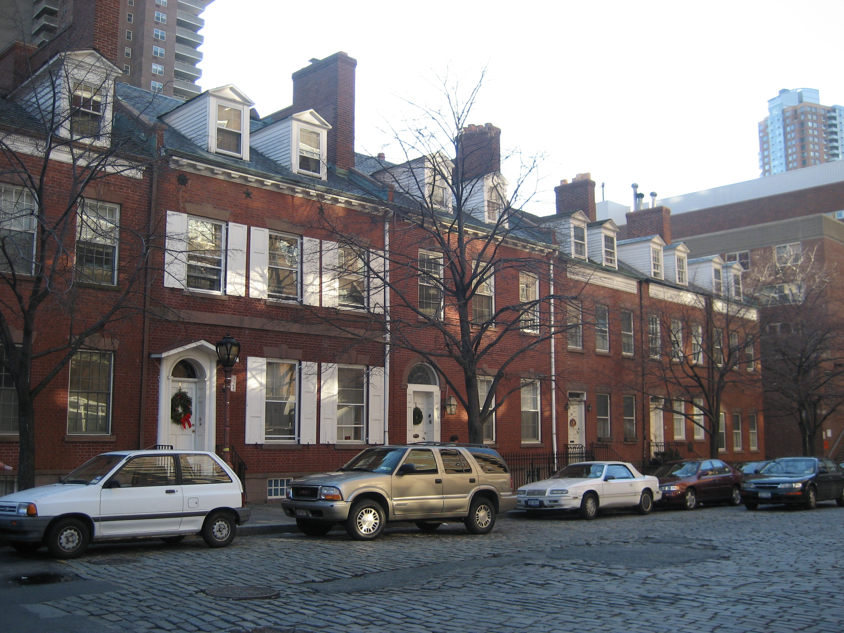 NYC - TriBeCa: Harrison Street Houses In the shadows of Independence Plaza, on Harrison St, stand a row of six restored 18th-century townhouses, known as the Harrison Street Houses. They were originally elegant Federal houses, recycled as produce market buildings. Three of them were built on Harrison Street and the rest relocated from a now extinct part of Washington Street 2 blocks away, which was demapped as part of the Independence Plaza project in 1975. Harrison St. was named after George Harrison (not the Beatle), whose brewery once stood near this location in the Pre-Revolutionary mid-18th century. 25 Harrison Street and 27 Harrison Street were built by John McComb, Jr., New York's first home-grown architect and designer of City Hall, Hamilton Grange, the James Watson House and Castle Clinton. #25 is known as the Old Wool House. It was originally sitted at 315 Washington Street and dates to 1819. #27 is the old McComb house, where the architect lived. It was originally sitted at 317 Washington Street and dates to 1796. The other houses relocated from Washington Street include the Jonas Wood House (314 Washington, 1804), Wilson Hunt House (327 Washington, 1828), Joseph Randolph House (329 Washington, 1828) and William R. Nichols House (331 Washington, 1828). 29 Harrison Street, original the Sarah R. Lambert House; 331 Harrison Street, originally the Jacob Ruckle House; and 33 Harrison Street, originally the Ebenezer Miller House, all date to 1827 and are on their original site. 25-41 Harrison Street were designated as individual landmarks by the New York Landmarks Preservation Commission in 1969.