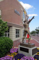Boston University: Agganis Arena - Harry Agganis statue The portrait statue of Harry Agganis by sculptor Armand LaMontagne was unveiled May 4, 2004 at Meze restaurant in Charlestown before being permanently installed outside of the Agganis Arena at Boston University on the corner of Commonwealth Avenue and Harry Agganis Way, formerly Gaffney Street. Aristotle George (Harry) Agganis (SED '54), "The Golden Greek" was a native of Lynn, Massachusetts and a football and baseball standout for the Boston University Terriers. After a sophomore season in 1949 in which he set a school record with fifteen touchdown passes, Harry entered the Marine Corps where he served fifteen months during the Korean War. Returning to college in 1951, he became the school's first All-American, setting the school record for 1,402 yards passing and winning the Bulger Lowe Award as New England's outstanding football player. That year, as a first baseman, he hit .322. Following his junior season, he was drafted by the Cleveland Browns in the first round of the 1952 NFL Draft, but instead signed to play first base for the Boston Red Sox for $35,000. Following his 1953 graduation, Agganis played with AAA Louisville before making his major league debut in 1954. As a rookie, he was a standout defensive player. In his second season, he got off to a good start, hitting .313 in his first 25 games before being hospitalized with pneumonia on June 2. He rejoined the team, but fell ill again in Kansas City on June 27 and was flown back to Cambridge, where he died of a pulmonary embolism at the age of 26. Agganis was inducted into the College Football Hall of Fame. Agganis Arena, located at 925 Commonwealth Avenue, was dedicated in 2004 and opened on January 3, 2005 when the the Boston Terriers ice hockey team defeated the Minnesota Golden Gophers by a score of 2-1 on Jack Parker Rink, named after the college hockey's winningest head coach who has guided the team since 1973. Ironically, the Terriers had lost by the very same score to the same team the day before in their old arena, the legendary Walter Brown Arena. Agganis Arena is a 29,000 square foot venue with 6,300 seats that expands to over 7,2000 seats for concerts and other events. In addition to serving as the home to the Boston University Terriers ice hockey team, is hosts BU basketball games, concerts, regional athletic tournaments, trade shows and other Boston University events. The arena is part of Boston University's John Hancock Student Village, or StuVi, a $225-million, 10-acre residential and recreational complex between Buick Street and Nickerson Field on ground formerly occupied by a National Guard Armory.