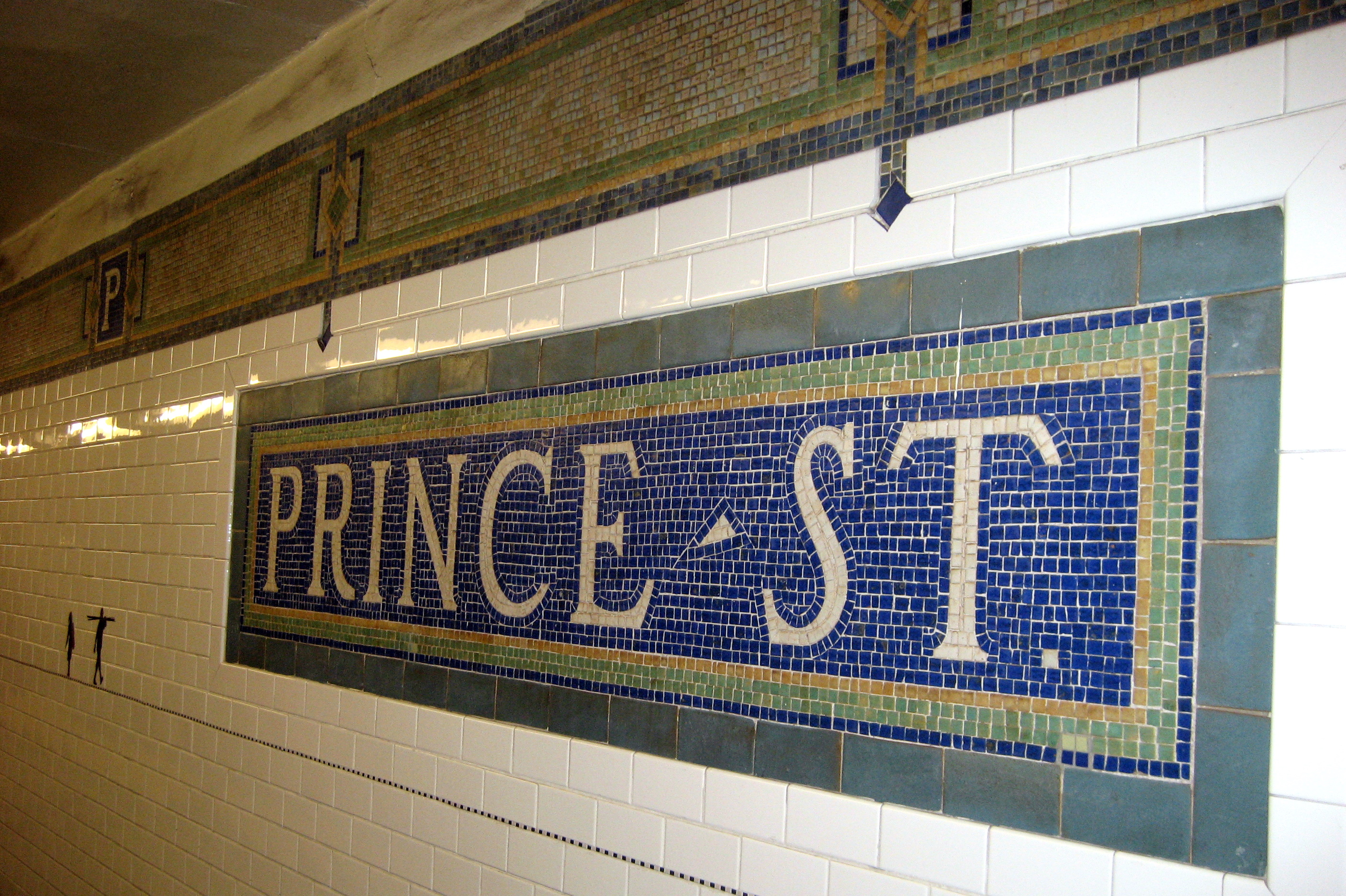 NYC - SoHo: Prince Street Station Opened on April 14, 1918, the Prince Street station, on the BMT Broadway line, services the N, R and W trains. A renovation in 2001 restored the original name tablet mosaics and tile band. Prince Street was named by the British and was one of the few streets not to be renamed after the Revolution. The platform walls are adorned with the 2004 artwork, Carrying On, by Janet Zweig and Edward Del Rosario. The water jet-cut steel, marbele, and slate frieze running a total of 1,200 feet is composed of 194 silhouettes of people hauling "stuff" with them as they walk the city streets and subways.