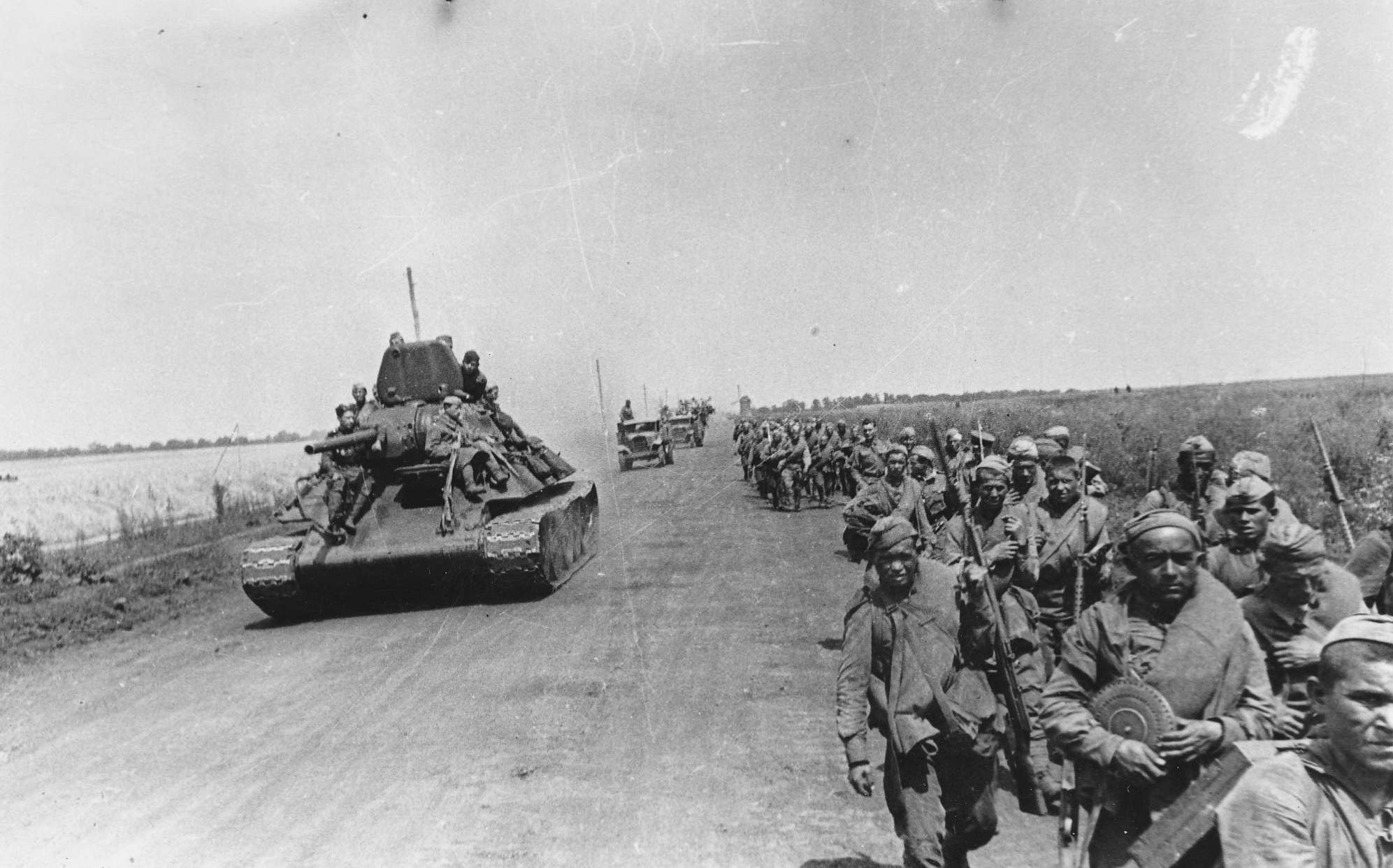Танк Т-34 и колонна советских солдат на марше по дороге под Белгородом.