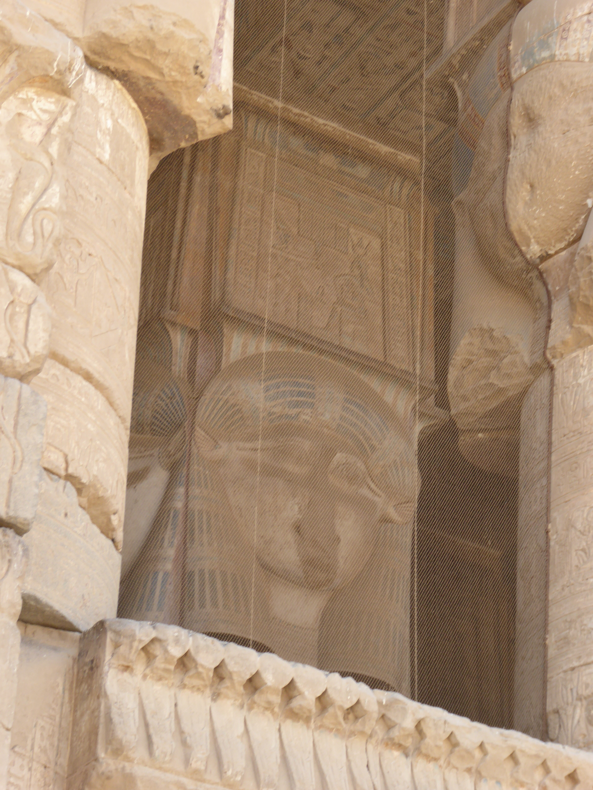 Hathor Capital, Dendera The Temple of Hathor at Dendera is one of Egypt's best preserved and most beautiful ancient shrines. This magnificent edifice dates to the Ptolemaic period, late in Egyptian history, though the site long had been the cult centre for the goddess Hathor for centuries before (the earliest extant remains date to c360BC but a temple is recorded here as far back as c2250BC). Most of the main building dates to the reigns of the last Cleopatras and further decoration and building work within the complex continued in the Roman period up to the reign of Trajan. The dominant structure in the complex is the Temple of Hathor, an enormous structure with a rectangular facade punctuated by the Hathor-headed columns of the hypostyle hall within. This hall is an architectural wonder, a masterpiece of ancient Egyptian design and decoration, which covers every surface and has been recently cleaned, revealing a superb astrological ceiling in all its original vibrant colours. Sadly there was much iconoclasm here during the early Christian period and most of the reliefs of the walls and pillars have been defaced. Worse still is the damage to the 24 Hathor-head capitals: not one of the nearly a hundred huge faces of the goddess that once smiled down on this hall has been left unblemished, most with their features cruelly chiselled away. The main temple building is otherwise structurally intact, and extends into further halls and chapels beyond, again with much relief decoration (much of which is again defaced). In one corner is an entrance to a crypt below, an unusual feature in Egyptian temple architecture consisting of several narrow passages adorned with carved relief decoration in good condition. There are further sanctuaries and chapels above on the roof of the temple, accessed by a decorated staircase and including the room where the famous Dendera Zodiac was formerly located (today its place in the ceiling taken by a cast of the original, now displayed in Paris). The highest part of the roof complex is no longer accessible to tourists, but I can still recall making the ascent there on our first visit in 1992. Several other buildings surround the main temple, the most impressive of which is the mammisi or 'birth-house'. This consists of a large rectangluar hall surrounded by a colonnade near the entrance to the site and has some well preserved relief decoration on its exterior. Most of this structure dates to the Roman period, but the ruins of its predecessor built under Nectanebo II (Egypt's last native pharoah) stand nearby. Dendera temple is one of the most rewarding in Egypt and shouldn't be missed. It is one of the most complete and evocative ancient monuments in the country and its recent restoration has revealed a surprisingly extensive amount of colour surviving within (we were amazed by the dramatic contrast with the soot-blackened ceiling we'd beheld on our previous visit in the 1990s). Despite its relative youth (in Egyptian terms at least!) it is easily one of my favourite sites in Egypt. en.wikipedia.org/wiki/Dendera_Temple_complex