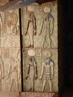 Lintel with Deities, Dendera Temple The Temple of Hathor at Dendera is one of Egypt's best preserved and most beautiful ancient shrines. This magnificent edifice dates to the Ptolemaic period, late in Egyptian history, though the site long had been the cult centre for the goddess Hathor for centuries before (the earliest extant remains date to c360BC but a temple is recorded here as far back as c2250BC). Most of the main building dates to the reigns of the last Cleopatras and further decoration and building work within the complex continued in the Roman period up to the reign of Trajan. The dominant structure in the complex is the Temple of Hathor, an enormous structure with a rectangular facade punctuated by the Hathor-headed columns of the hypostyle hall within. This hall is an architectural wonder, a masterpiece of ancient Egyptian design and decoration, which covers every surface and has been recently cleaned, revealing a superb astrological ceiling in all its original vibrant colours. Sadly there was much iconoclasm here during the early Christian period and most of the reliefs of the walls and pillars have been defaced. Worse still is the damage to the 24 Hathor-head capitals: not one of the nearly a hundred huge faces of the goddess that once smiled down on this hall has been left unblemished, most with their features cruelly chiselled away. The main temple building is otherwise structurally intact, and extends into further halls and chapels beyond, again with much relief decoration (much of which is again defaced). In one corner is an entrance to a crypt below, an unusual feature in Egyptian temple architecture consisting of several narrow passages adorned with carved relief decoration in good condition. There are further sanctuaries and chapels above on the roof of the temple, accessed by a decorated staircase and including the room where the famous Dendera Zodiac was formerly located (today its place in the ceiling taken by a cast of the original, now displayed in Paris). The highest part of the roof complex is no longer accessible to tourists, but I can still recall making the ascent there on our first visit in 1992. Several other buildings surround the main temple, the most impressive of which is the mammisi or 'birth-house'. This consists of a large rectangluar hall surrounded by a colonnade near the entrance to the site and has some well preserved relief decoration on its exterior. Most of this structure dates to the Roman period, but the ruins of its predecessor built under Nectanebo II (Egypt's last native pharoah) stand nearby. Dendera temple is one of the most rewarding in Egypt and shouldn't be missed. It is one of the most complete and evocative ancient monuments in the country and its recent restoration has revealed a surprisingly extensive amount of colour surviving within (we were amazed by the dramatic contrast with the soot-blackened ceiling we'd beheld on our previous visit in the 1990s). Despite its relative youth (in Egyptian terms at least!) it is easily one of my favourite sites in Egypt. en.wikipedia.org/wiki/Dendera_Temple_complex