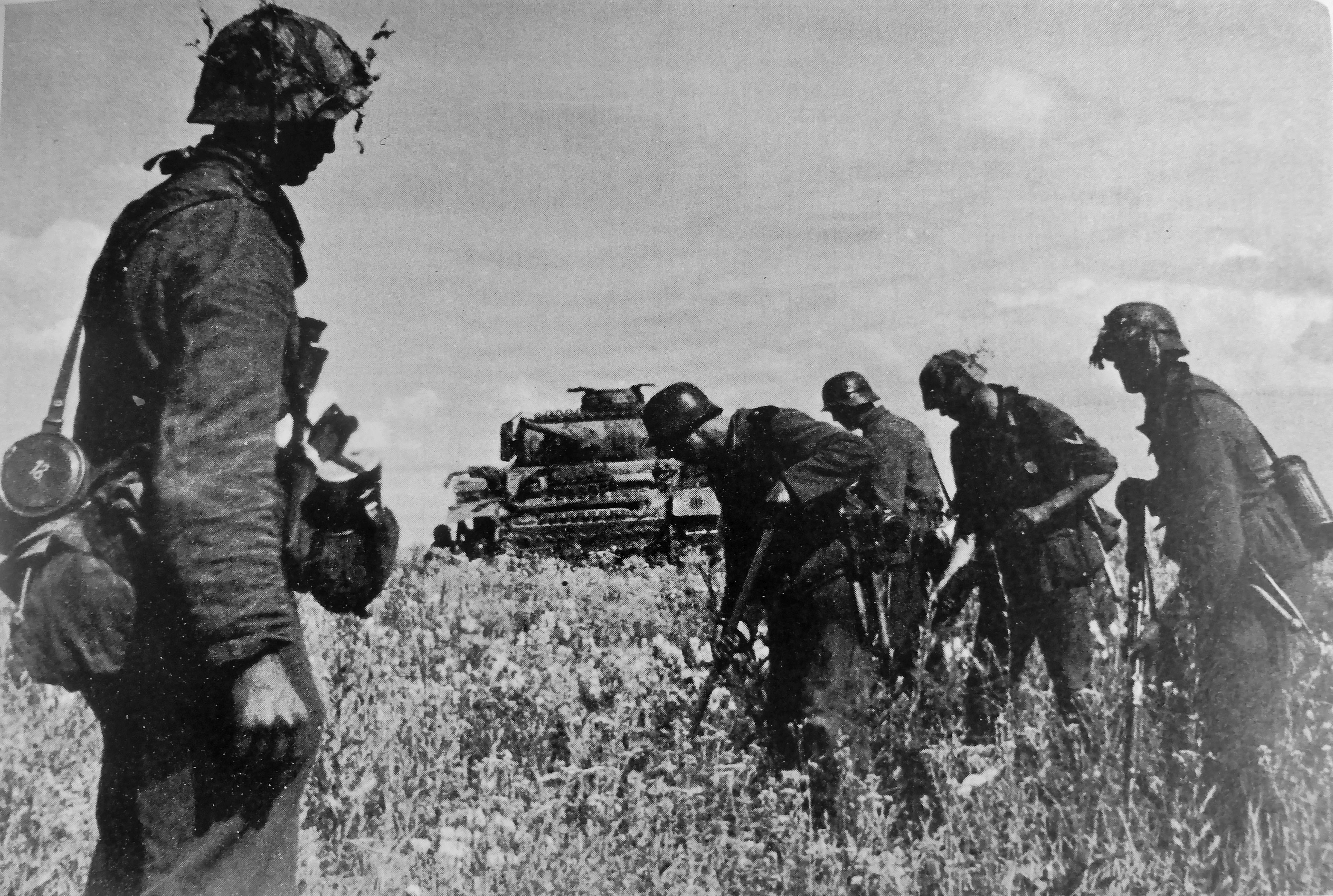 Немецкие солдаты ищут мины на поле перед боями на Курской дуге. На заднем плане находится танк Pz.Kpfw. III.