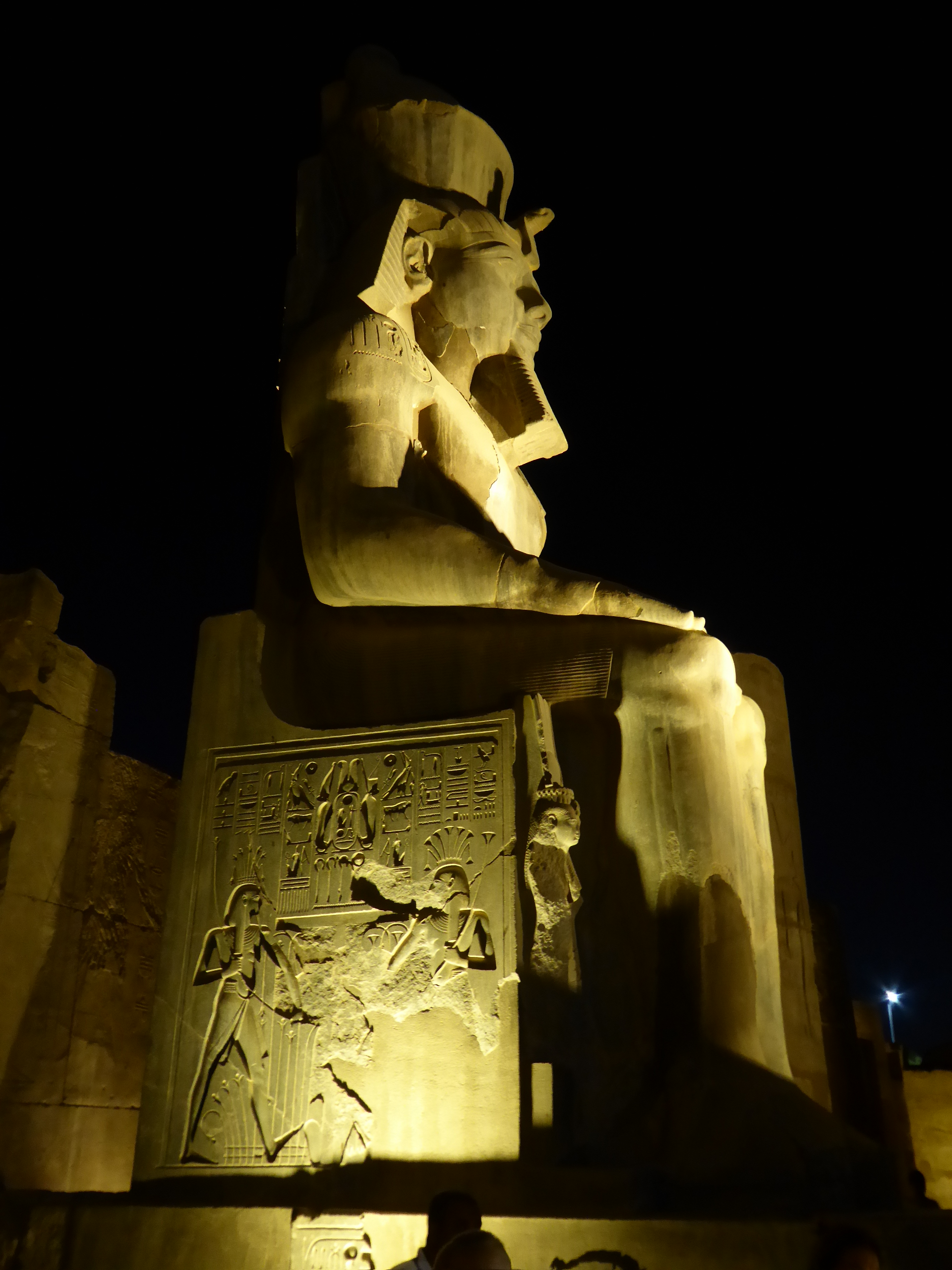 Ramesses Colossus, Luxor Temple Luxor Temple stands in the heart of the modern city close to the banks of the Nile. It is an impressive and largely complete structure dating back to the New Kingdom, constructed around c1400BC. Its main facade is still adorned with large sculptures of Ramesses II, along with one of a pair of obelisks that flanked the main entrance (the other now famously stands in Paris). The earliest parts of the complex were built under Pharoah Amenhotep III, with the main shrine (with later rebuilding by Alexander) and the papyrus-columned courtyard at the southern end dating from his reign. Also of this date is the monumental colonnade that forms the centre of the complex, with a mighty avenue of columns flanked by corridors finished by Amenhotep III's grandson, Tutankhamun. The first parts of the temple the visitor encounters, the facade with its twin pylon-towers followed by the colonnaded first courtyard date from the following dynasty and were mostly constructed during the reign of Ramesses II, whose colossal statues are omnipresent in these areas to make his authorship all the more apparent. The first courtyard is still partially occupied by a mosque dedicated to a local holy-man, Abu el Haggag. Attempts to relocate the shrine and reveal the hidden parts of the ancient structure beneath have so far been resisted. Finally the temple is preceded by an avenue of sphinxes that originally extended all the way to Karnak temple roughly a mile away. Much of the course of the avenue was recently excavated (at huge cost involving much demolition in central Luxor) and has not yet fully opened. The sphinxes at this southern end are the best preserved, and were installed by one of the very last native pharoahs, Nectanebo I. Our visit was rather late in the day, thus the light rapidly diminished on arrival, so we instead experienced the temple mostly floodlit, which was a rather magical experience. For more see below:- en.wikipedia.org/wiki/Luxor_Temple