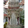 Prang Detail, Wat Arun, Bangkok Located close to the Chao Phraya riverfront on Bangkok's west bank, Wat Arun (the Temple of Dawn) is one of the city's most prominent landmarks; it's towering steeple-like stupa, surrounded by four smaller spires known as prangs, forms a unique shilouette, at first as reminiscent of a gothic cathedral as a normal Thai temple. The temple itself is located behind the stupa/pagoda and is a fairly extensive complex founded in the late 18th century, but it is generally the giant spire-stupa, built in the first half of the 19th century, that visitors focus on. The monument is almost entirely encrusted with porcelain mosaic decoration which extends to much of the figure sculpture (rows of crouching demons, monkey warriors and apsaras can be seen propping up the tower at various levels). Two terraces, one and two thirds up respectively, afford spectacular views over the temple complex and across the Chao Phraya and city centre beyond. The upper level however is only accessible via a terrifyingly steep staircase! en.wikipedia.org/wiki/Wat_Arun