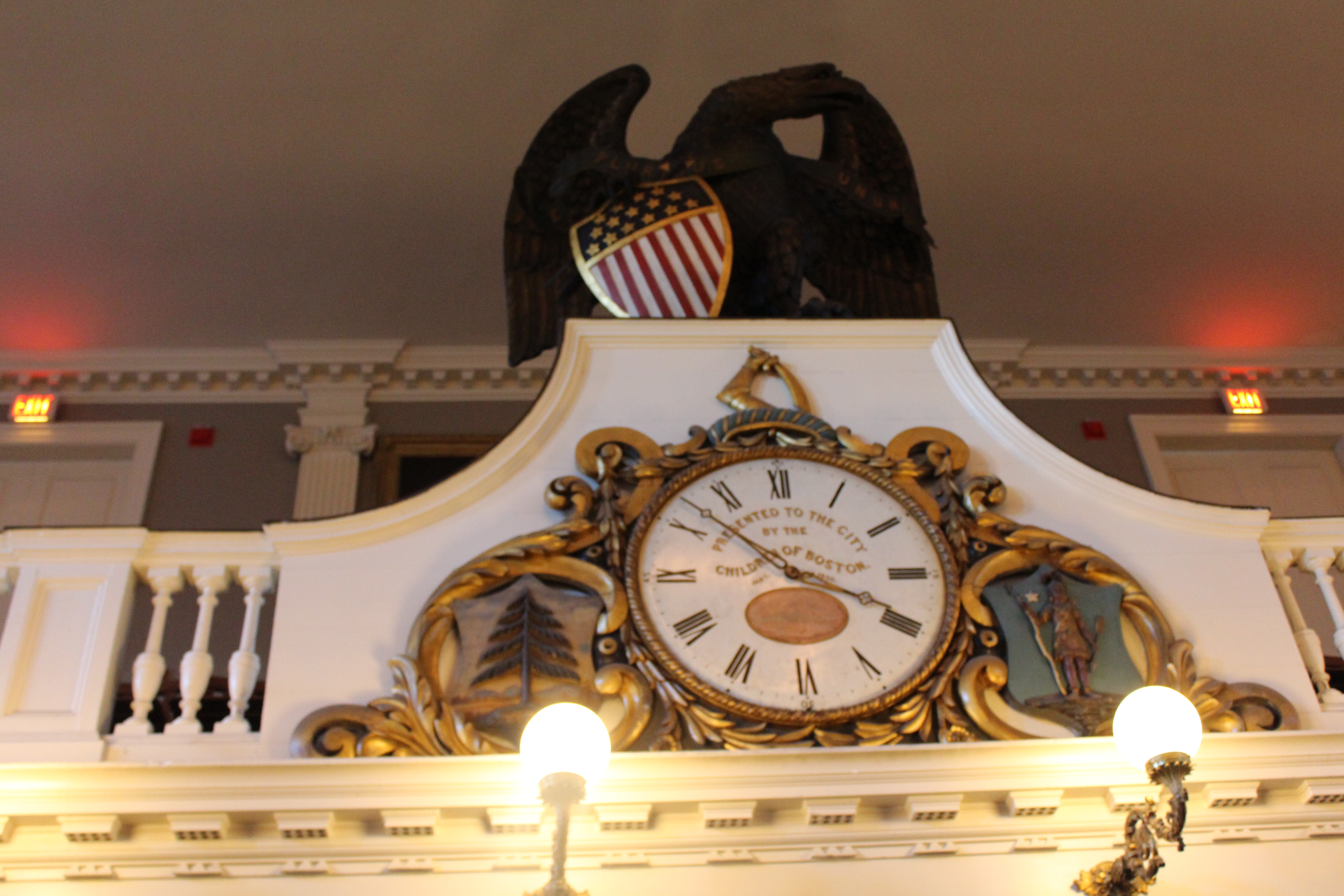 Boston - Freedom Trail: Faneuil Hall - Great Hall Faneuil Hall, part of the Boston National Historical Park and a well-known stop along the Freedom Trail, has served as a marketplace and meeting hall since 1742. Known as the "Cradle of Liberty", it was the site of several important events of the American Revolution including James Otis' re-dedication address in 1763, Samuel Adams' impassioned plea following the Boston Massacre in 1970 that eventually led to the establishment of the Committee of Correspondence here in 1772, and the first meeting in protest of the imposed tea tax in 1773 that ultimately led to the Boston Tea Party. The original Hall was built by artist John Smibert in 1740–1742 in the style of an English country market, with an open ground floor and an assembly room above. The 38-pound, 52-inch gilded grasshopper weathervane on top of the building was created by silversmith Shem Drowne in 1742 and was modeled on the grasshopper weathervane on the London Royal Exchange. Funded by a wealthy Boston merchant, Peter Faneuil, who died shortly after the building was completed. Almost destroyed by a fire in 1761, it was rebuilt with funds raised by the state lottery and re-opened in 1763. By 1806, the city had outgrown the hall and Charles Bulfinch was commissioned to expand the building--doubling the height and width, while managing to keep intact the walls from the original structure. Four new bays were added, to make seven in all; a third floor was added; the open arcades were enclosed; and the cupola was centered and moved to the east end of the building. Bulfinch applied Doric brick pilasters to the lower two floors, with Ionic pilasters on the third floor. This renovation added galleries around the assembly hall and increased its height. The building was entirely rebuilt in 1898–1899, of noncombustible materials. The building underwent a major internal renovation during the 1970's. Faneuil Hall is now part of the larger Faneuil Hall Marketplace, which includes three long granite buildings called North Market, Quincy Market, and South Market. Its success in the late 1970s led to the emergence of similar marketplaces in other U.S. cities. Inside the Hall are dozens of paintings of famous Americans, including the mural of Webster's Reply to Hayne and Gilbert Stuart's portrait of Washington at Dorchester Heights. The first floor operates as a market, while the second floor is taken up by the Great Hall, where Boston's town meetings were once held. The third floor houses the museum and armory of the Ancient and Honorable Artillery Company of Massachusetts. Founded in 1638, this is the oldest military company in the US, and considered the third oldest in the world. In recent history, Faneuil Hall was the home to President John F. Kennedy's last campaign speech and Senator John Kerry's concession speech in the 2004 presidential election. The Marketplace fronted by Miss Anne Whitney's Samuel Adams statue on Congress Street. In 2007, Faneuil Hall Marketplace was ranked #64 on the AIA 150 America's Favorite Architecture list. In 2008, Faneuil Hall was ranked #4 in America's 25 Most Visited Tourist Sites by Forbes Traveler. National Historic Register #66000368